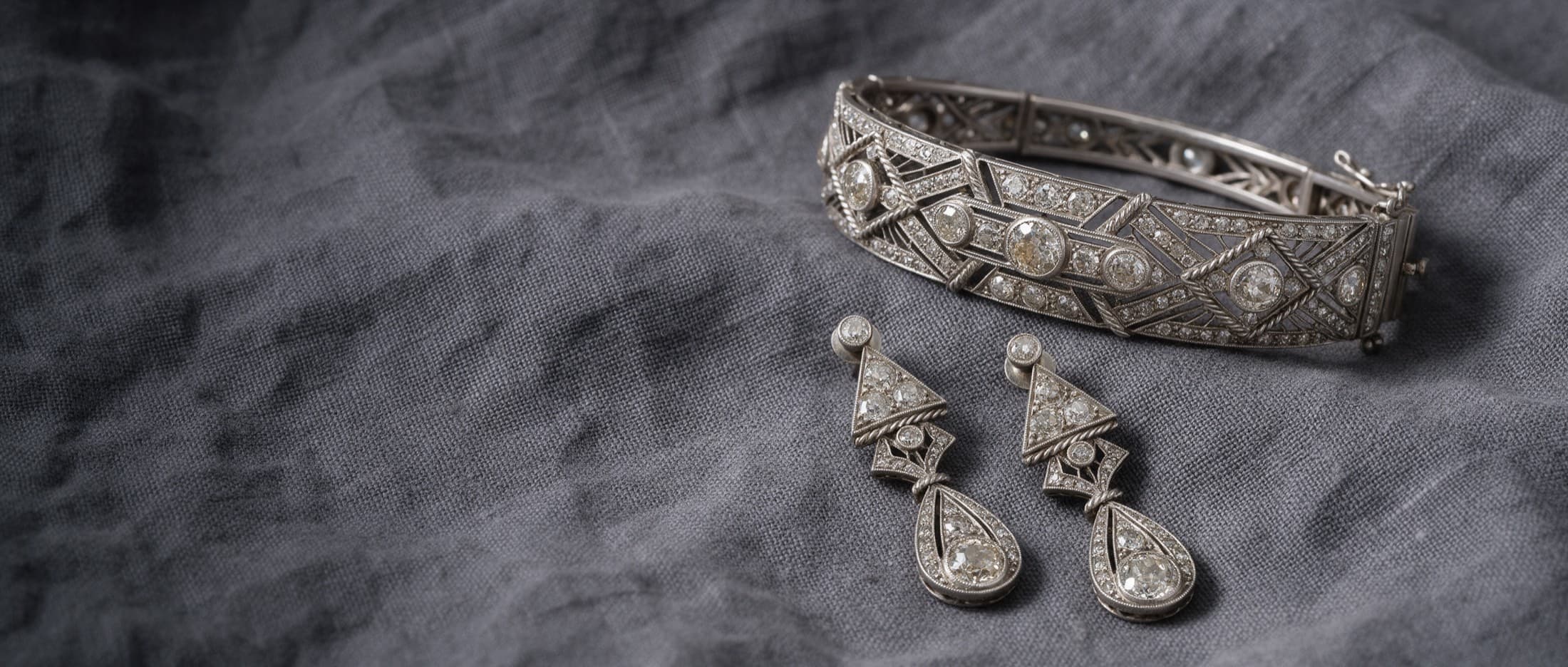 An Art Deco diamond and platinum bracelet with matching drop earrings on black stone