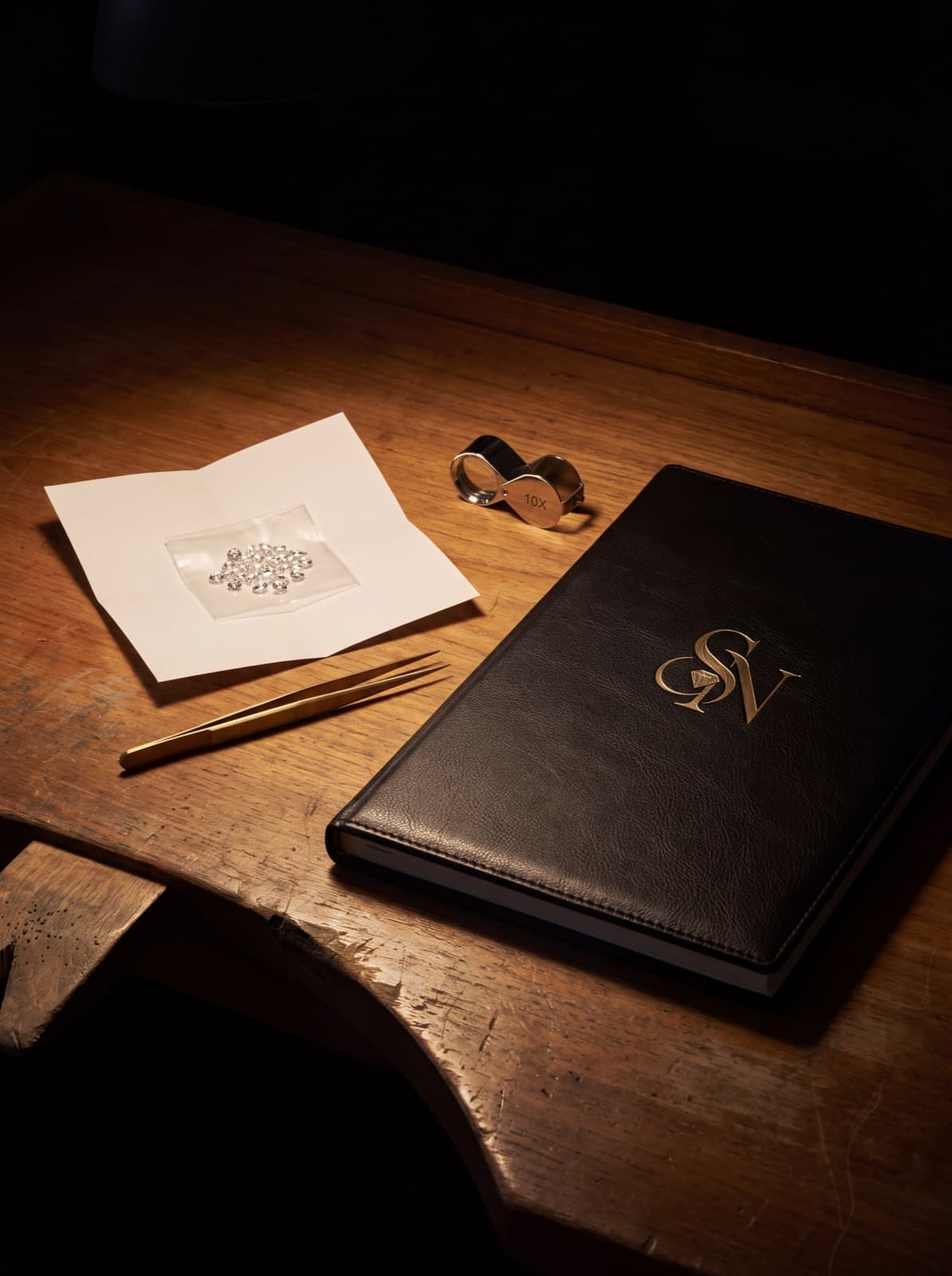 The Sayyid & Najjar Co. grading bench: a parcel of loose diamonds, brass tweezers, a loupe and the house ledger